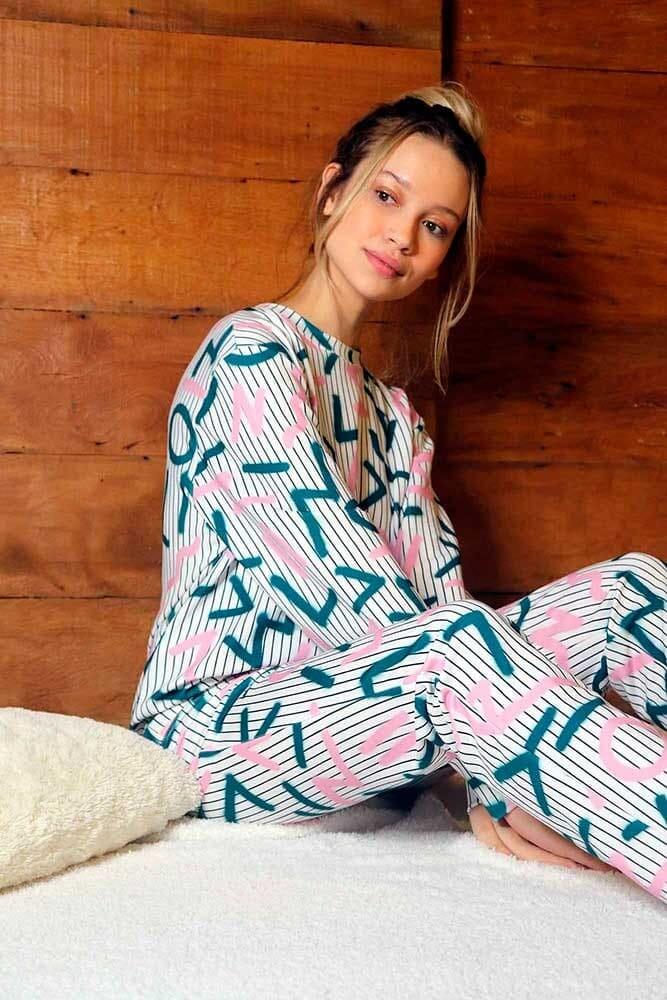 mulher sentada sobre sua cama, utilizando um conjunto Tjama.