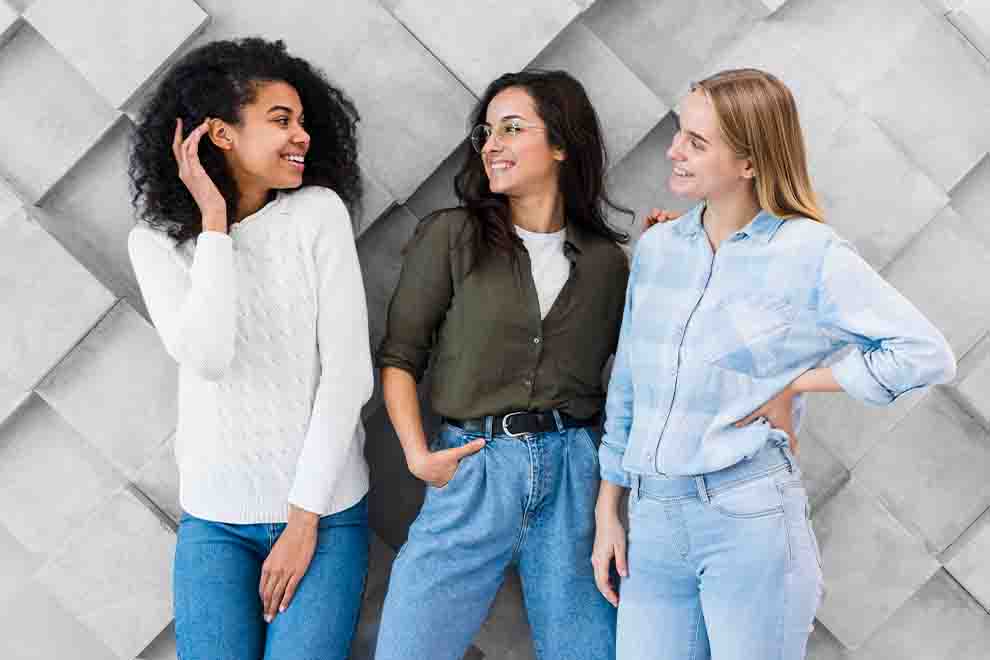 Três mulheres sorrindo em frente a parede texturizada.
