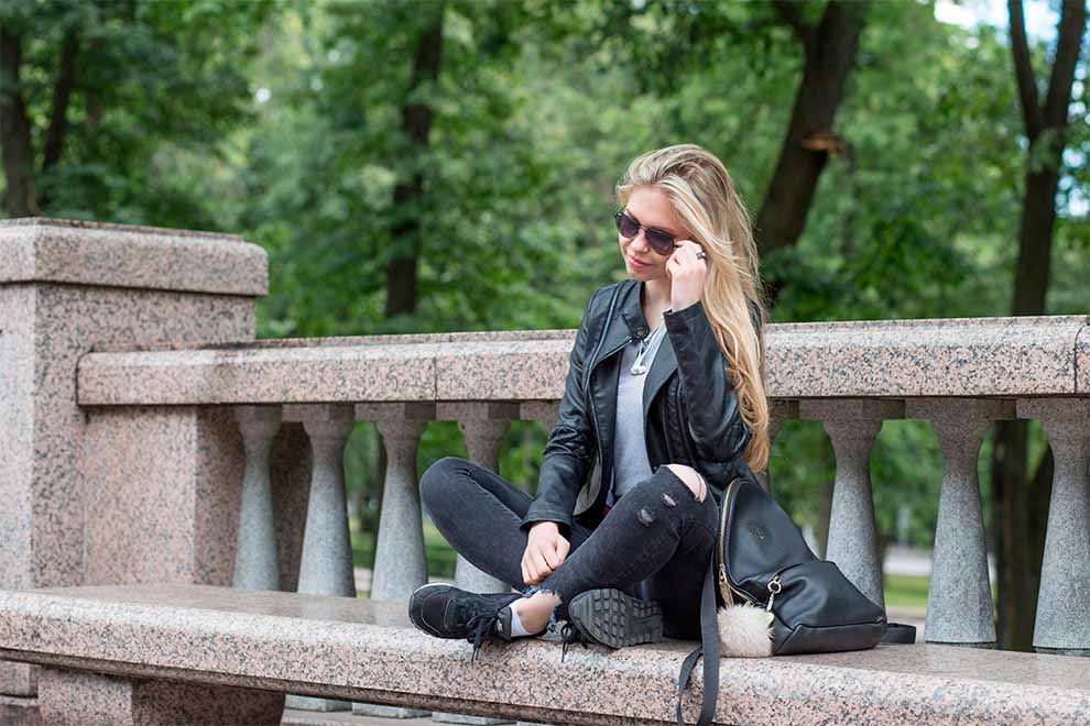 estilo dramatico urbano uma mulher sentada em um banco em concreto usando roupas no estilo drámatico urbano em um dia ensolarado