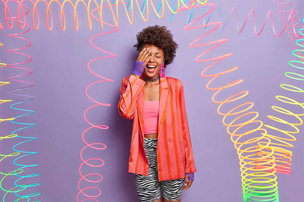 estilo criativo mulher com roupas coloridas e com diferentes estampas em um fundo lilás e enfeites divertidos