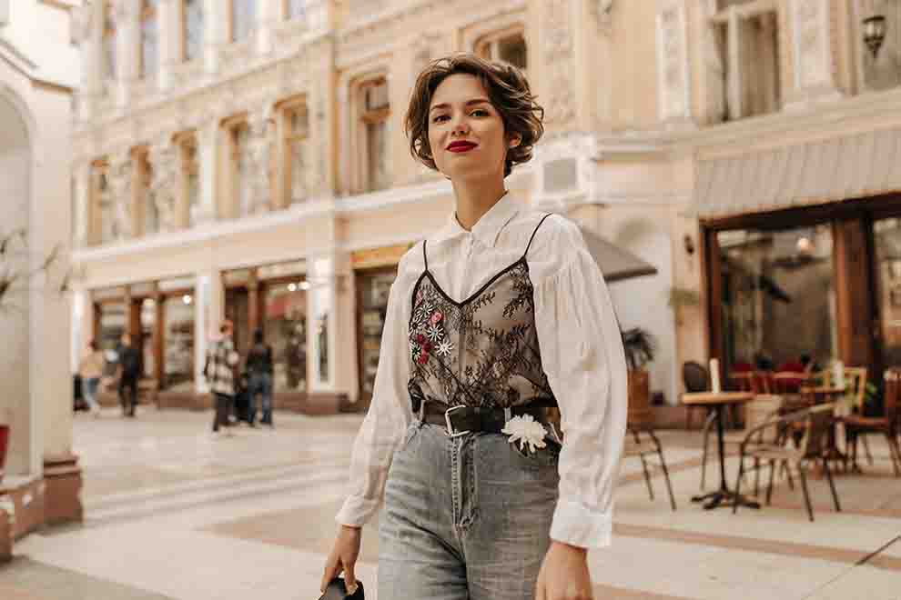 Mulher jovem com blusa branca e calça jeans em rua