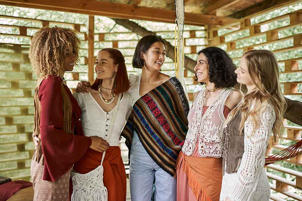 Cinco mulheres posando em ambiente rústico e alegre.
