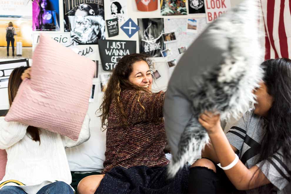 garotas fazendo uma guerra de travesseiros de forma divertida em uma festa do pijama 