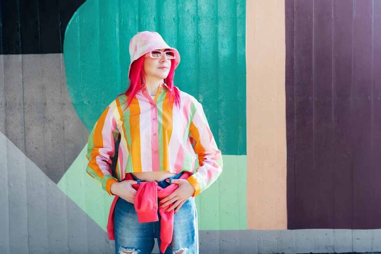Mulher com cabelo rosa em frente a parede colorida