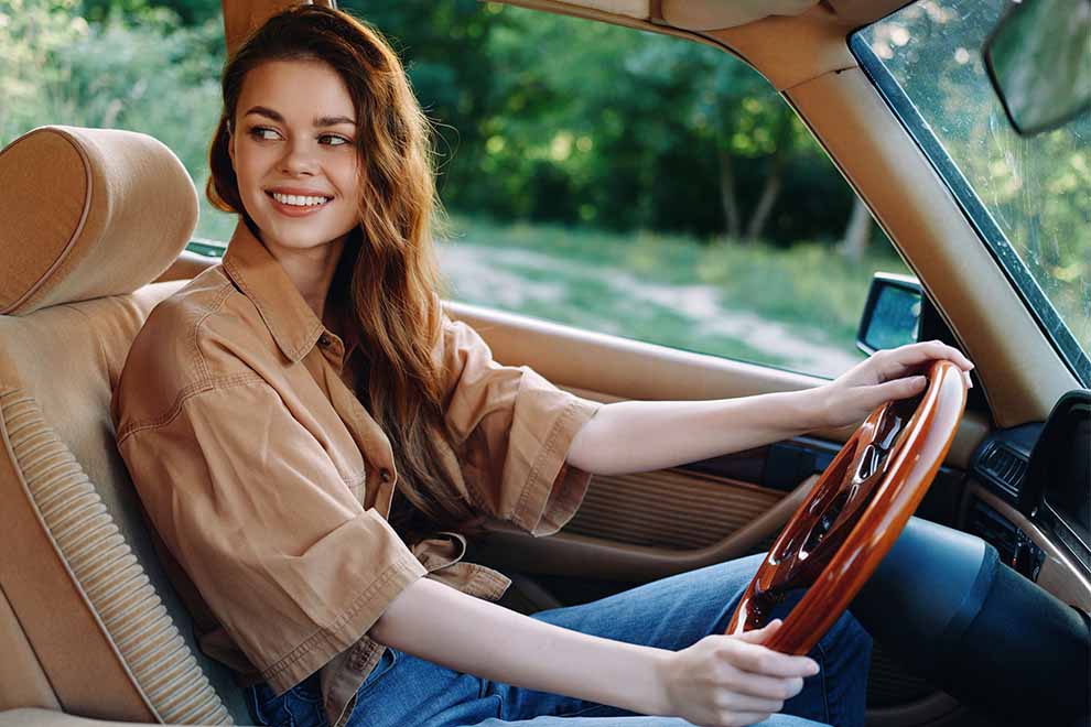 mulher usando uma camisa bege e calça jeans dirigindo um carro