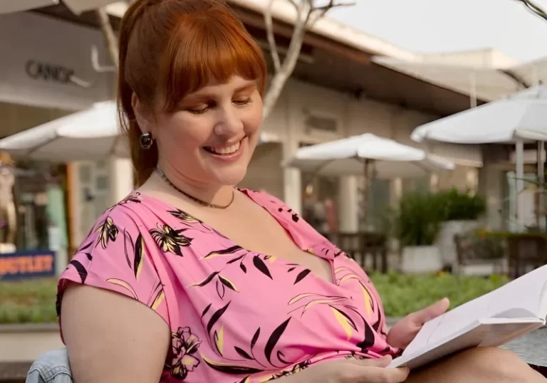mulher ruiva sorridente sentada ao ar livre lendo livre
