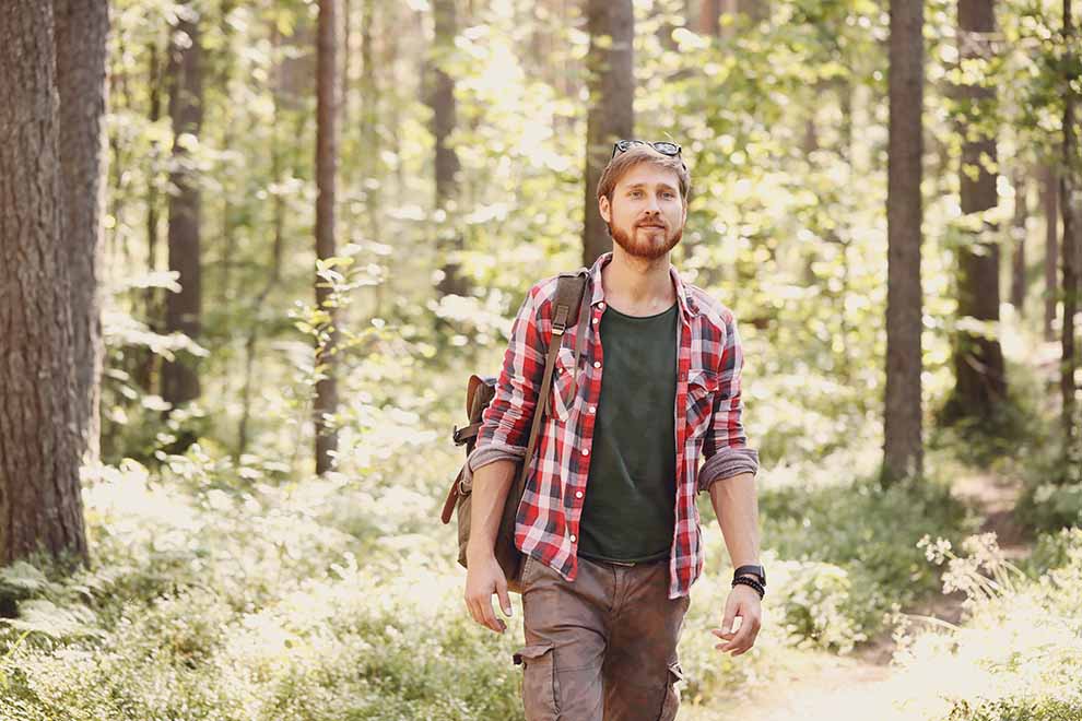 Homem caminhando em floresta com mochila