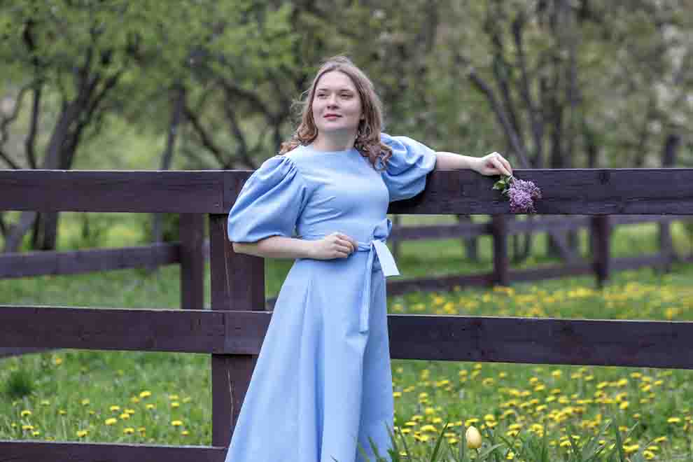 Mulher com vestido azul em campo florido