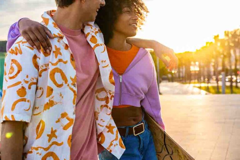 Casal sorrindo ao pôr do sol com prancha de surf