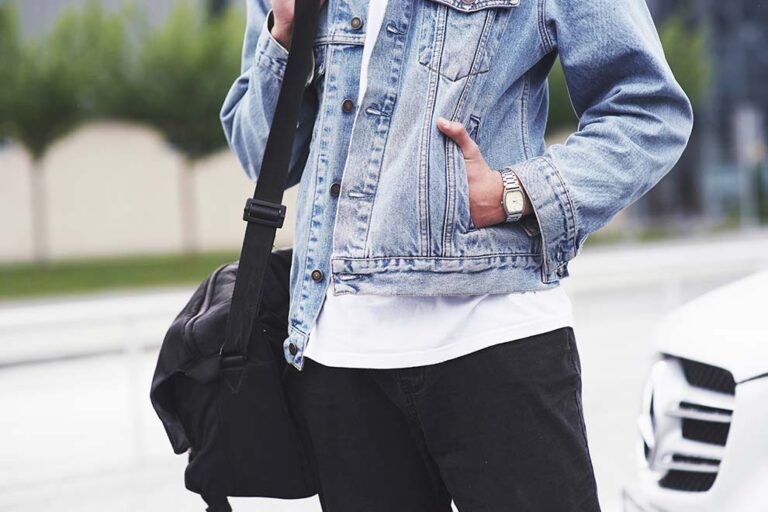 Homem com jaqueta jeans e bolsa sobre o ombro.