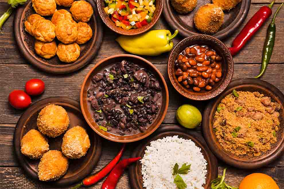 Prato colorido com feijão, arroz e salgados variados.