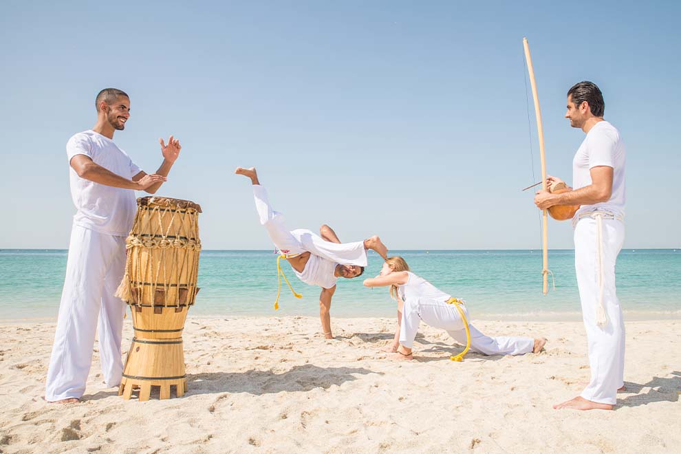Grupo praticando capoeira na praia ensolarada