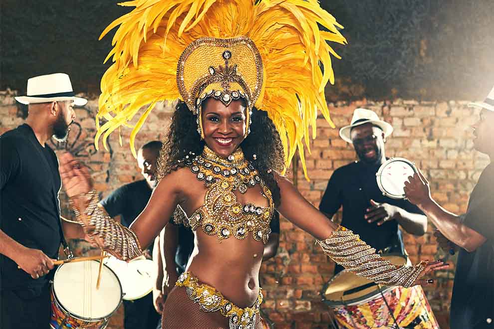 Dançarina com plumas amarelas e traje brilhante em festa.