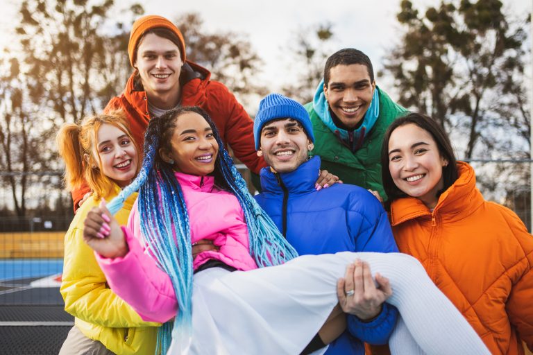 Grupo de amigos se divertindo ao ar livre com roupas coloridas.