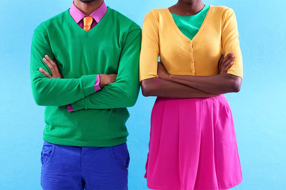 um casal de modelos usando roupas colorida sem cores analogas em um fundo azul claro